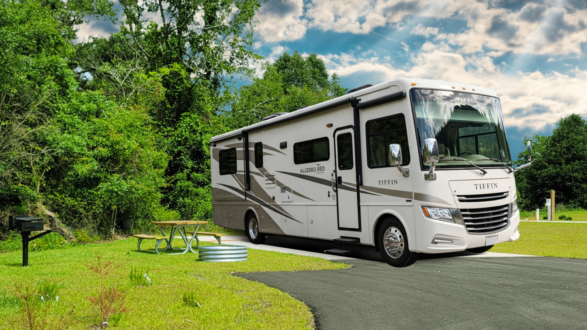 A luxury motorhome parked on a paved pad next to a picnic table and fire ring at Canopy Oaks Place